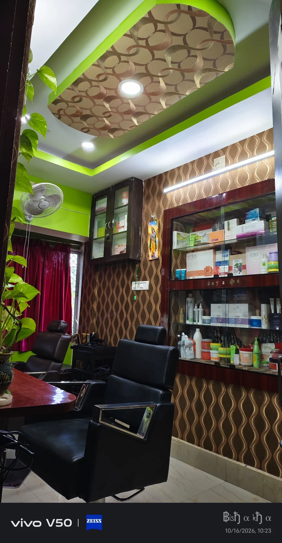 Jyoti Beauty Care salon interior with black styling chairs, product cabinets, patterned walls and green ceiling accents